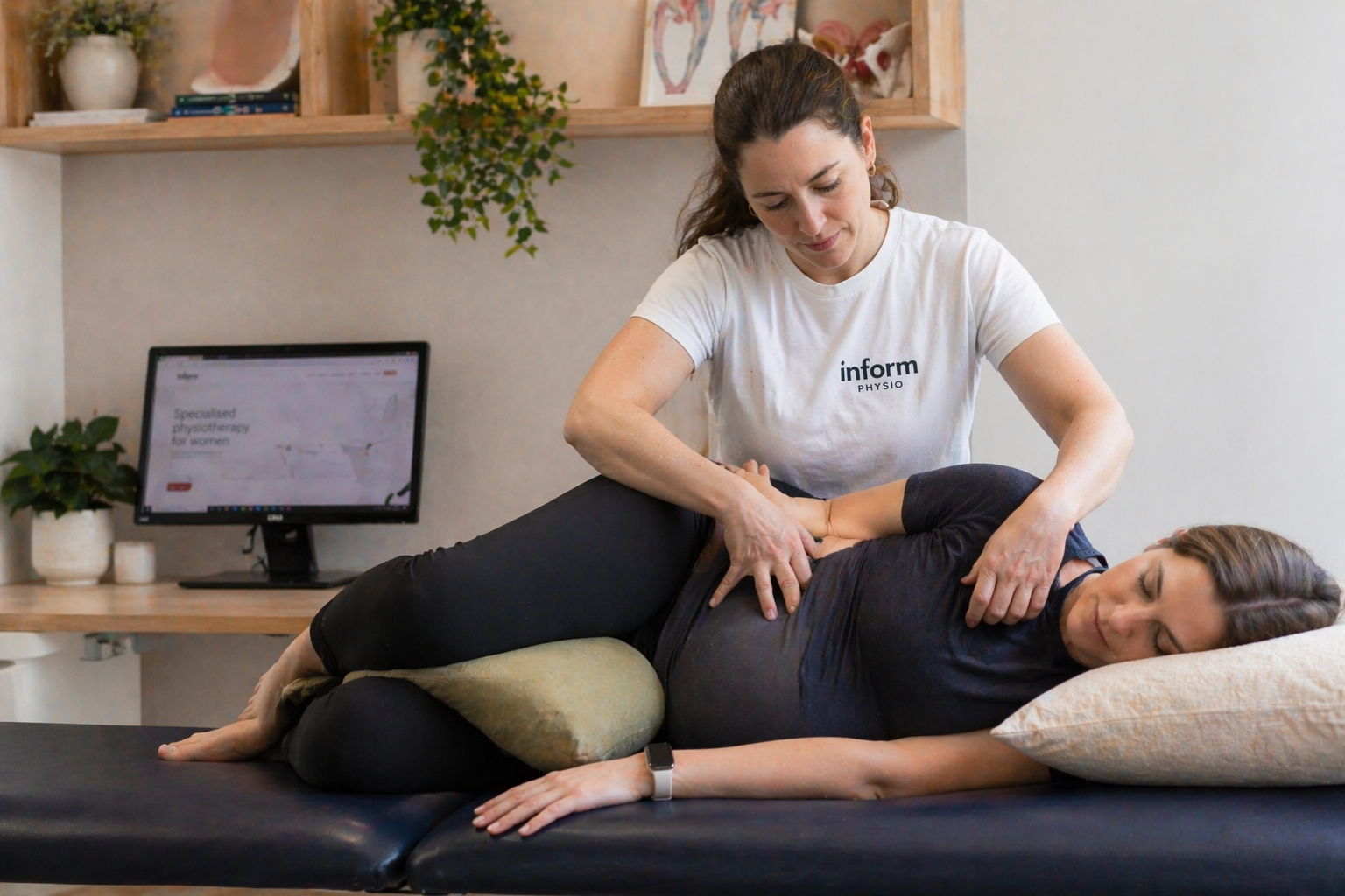 A physiotherapist working with a pregnant patient in a clinical setting, showing manual therapy or exercise guidance.